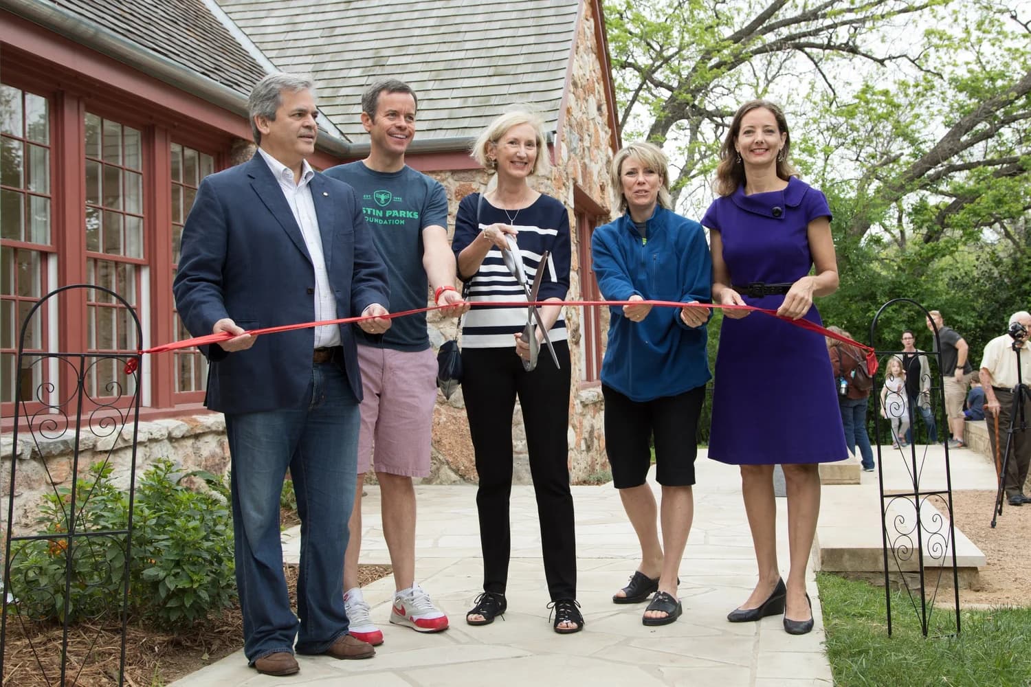A ribbon-cutting ceremony in front of a historic stone building in the park
