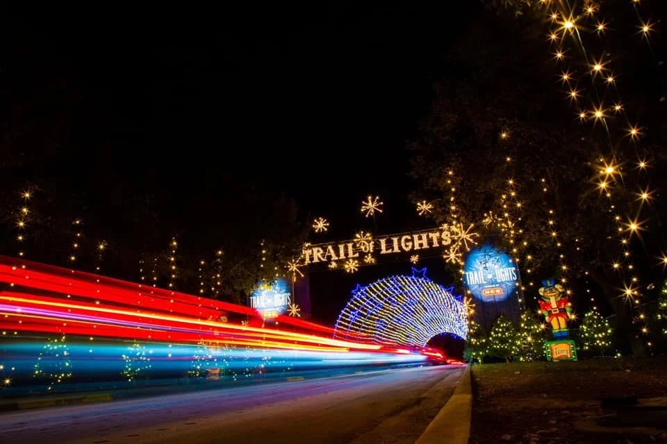 The illuminated entry arch of the Zilker Trail of Lights with light trails on the road
