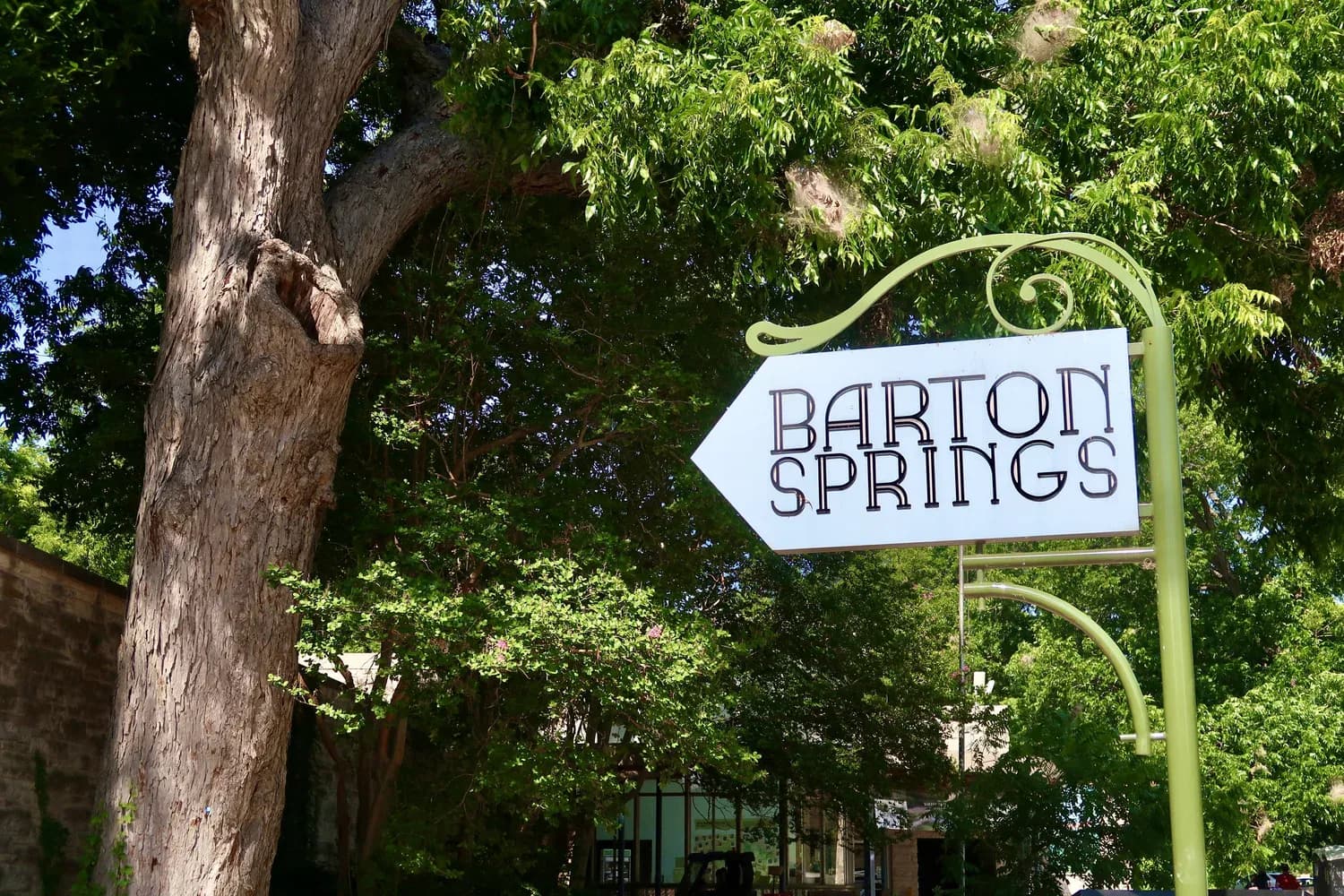 A vintage-style wrought-iron sign pointing the way to Barton Springs