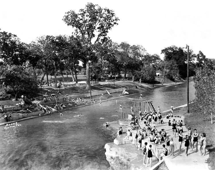A historic black-and-white photograph of crowds swimming at Barton Springs