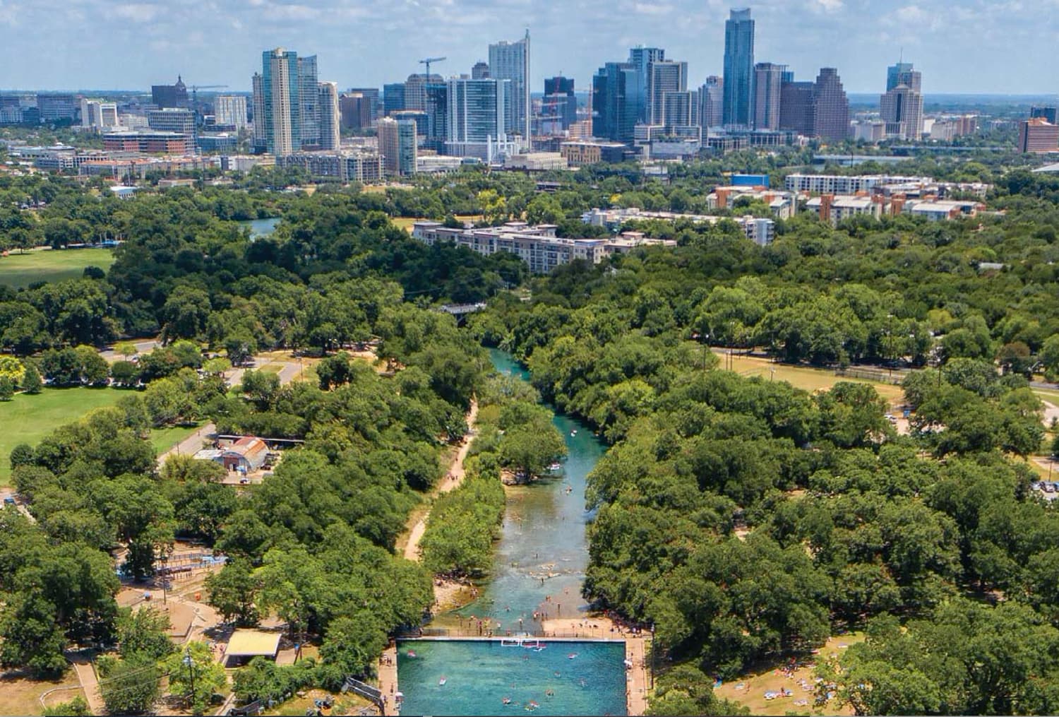 Aerial view of Barton Springs and Zilker Park with the downtown Austin skyline beyond