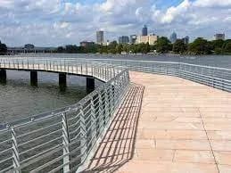 The boardwalk section of the Butler Hike-and-Bike Trail curving along Lady Bird Lake with the Austin skyline beyond
